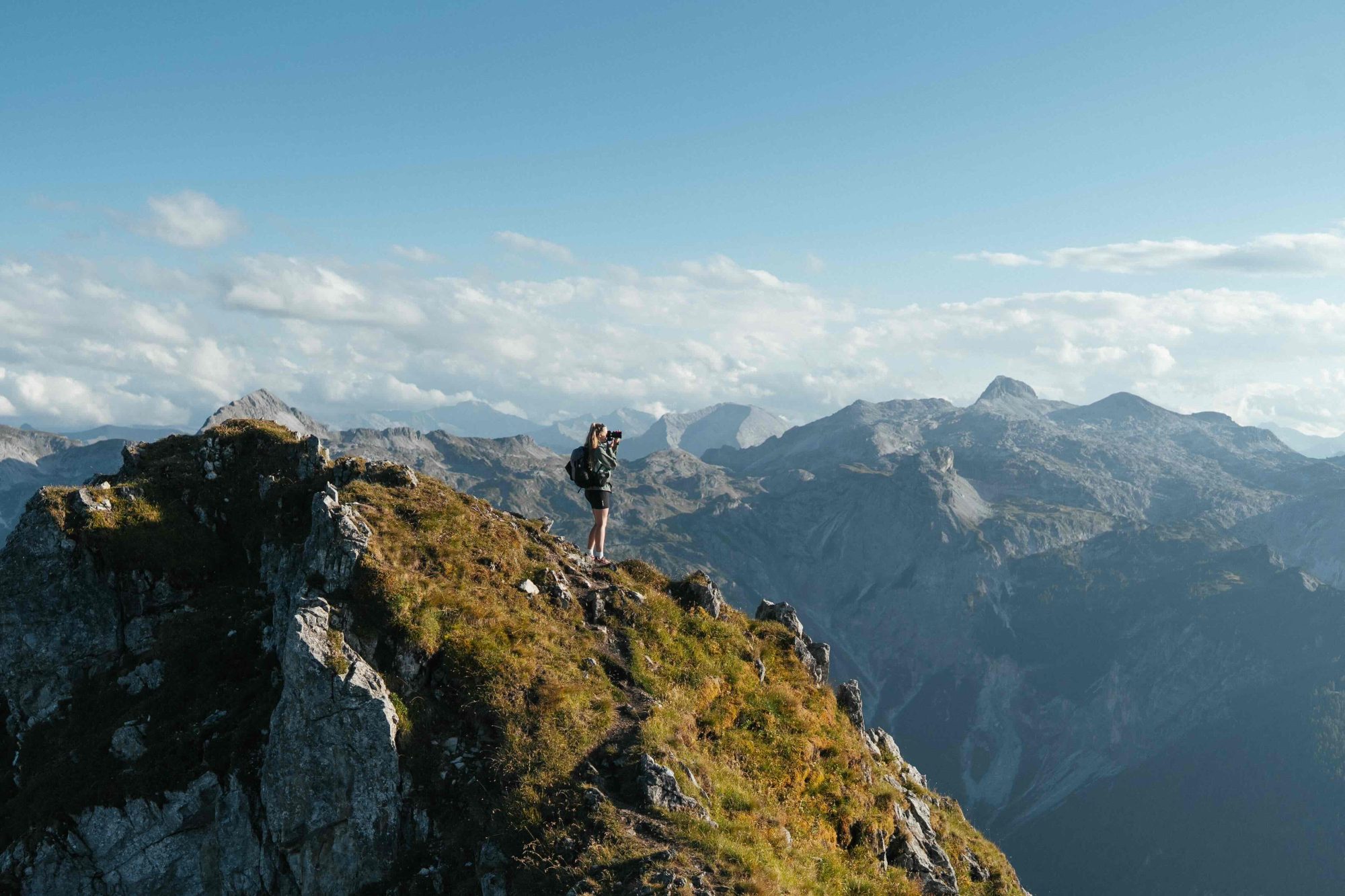 Female photographer on a mountain in Austria pointing her camera to the horizon